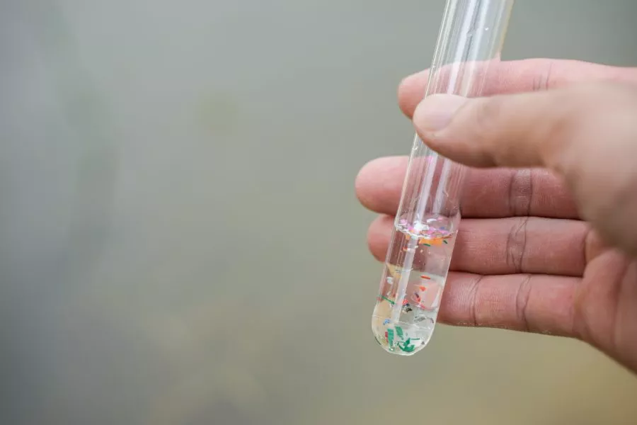 hand holding a tube of microplastics for mass pollution lawsuits