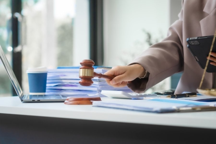Attractive Asian businesswoman in formal business attire is working at her desk with a laptop and mobile phone, focusing on corporate law, contracts, compliance, and law firm marketing strategies