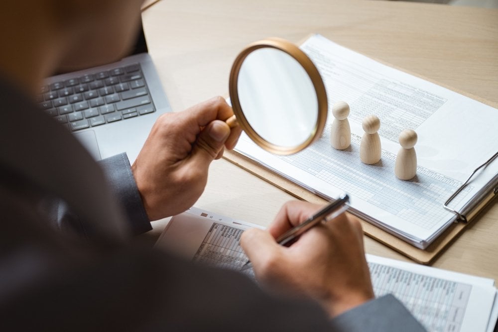 Chicago Fractional CMO Enhances QSR Marketing 1 Human resource recruit staff hiring. Hr recruitment. Employment job search. A man is holding a magnifying glass and writing on a piece of paper. Concept of focus and attention to detail
