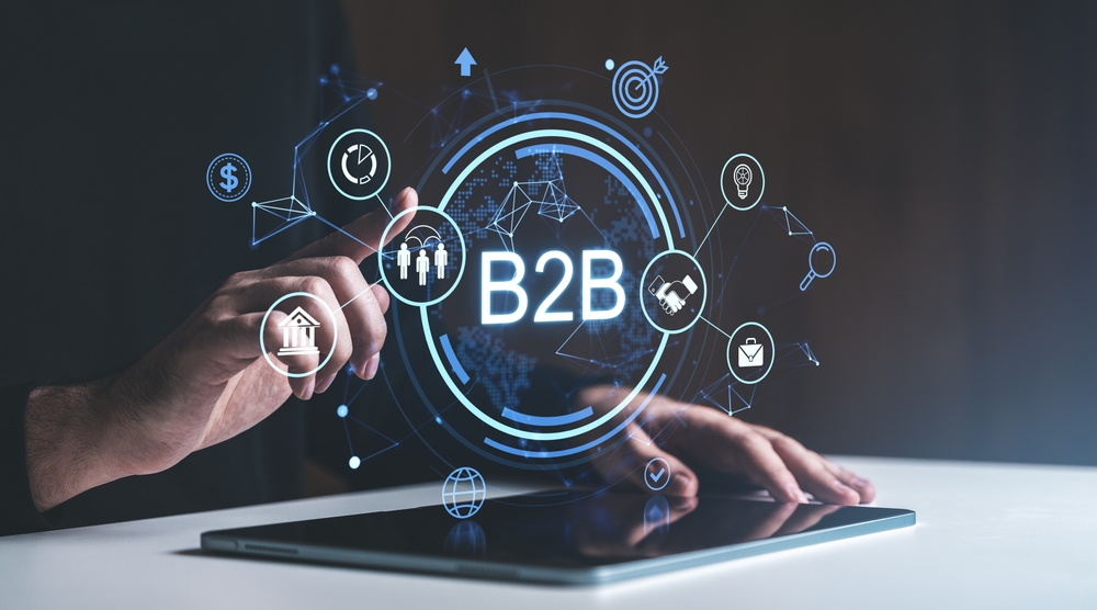 Hand pointing at glowing B2B icons on a digital screen with connected symbols, in a futuristic style on a dark background. Concept of business collaboration