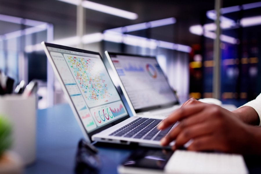 African American woman using virtual dashboard to predict emerging market trends in financial analytics for her business.