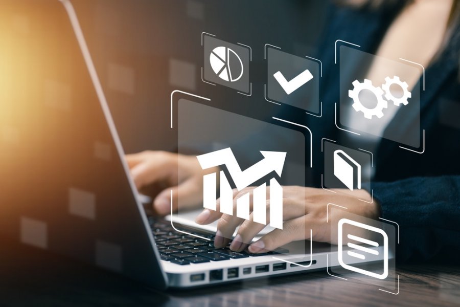 Hands typing on laptop with digital analytics dashboard, symbolizing business intelligence, data analysis, performance tracking, and strategic decision-making.