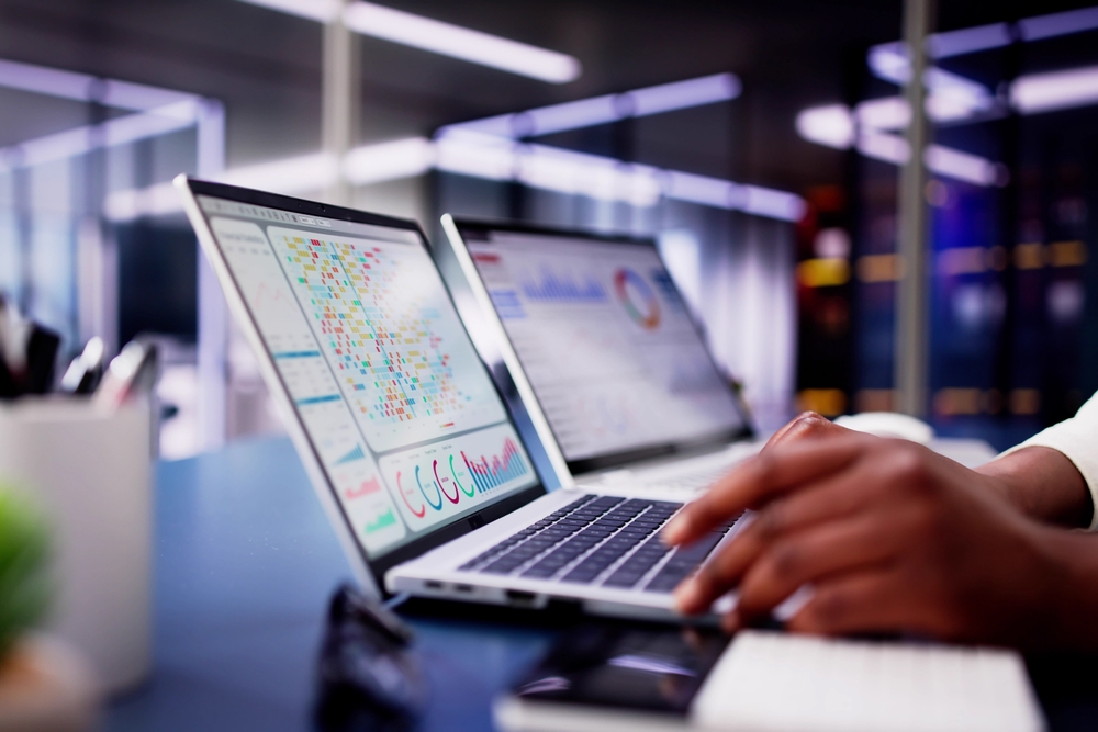 African American woman using virtual dashboard to predict emerging market trends in financial analytics for her business.